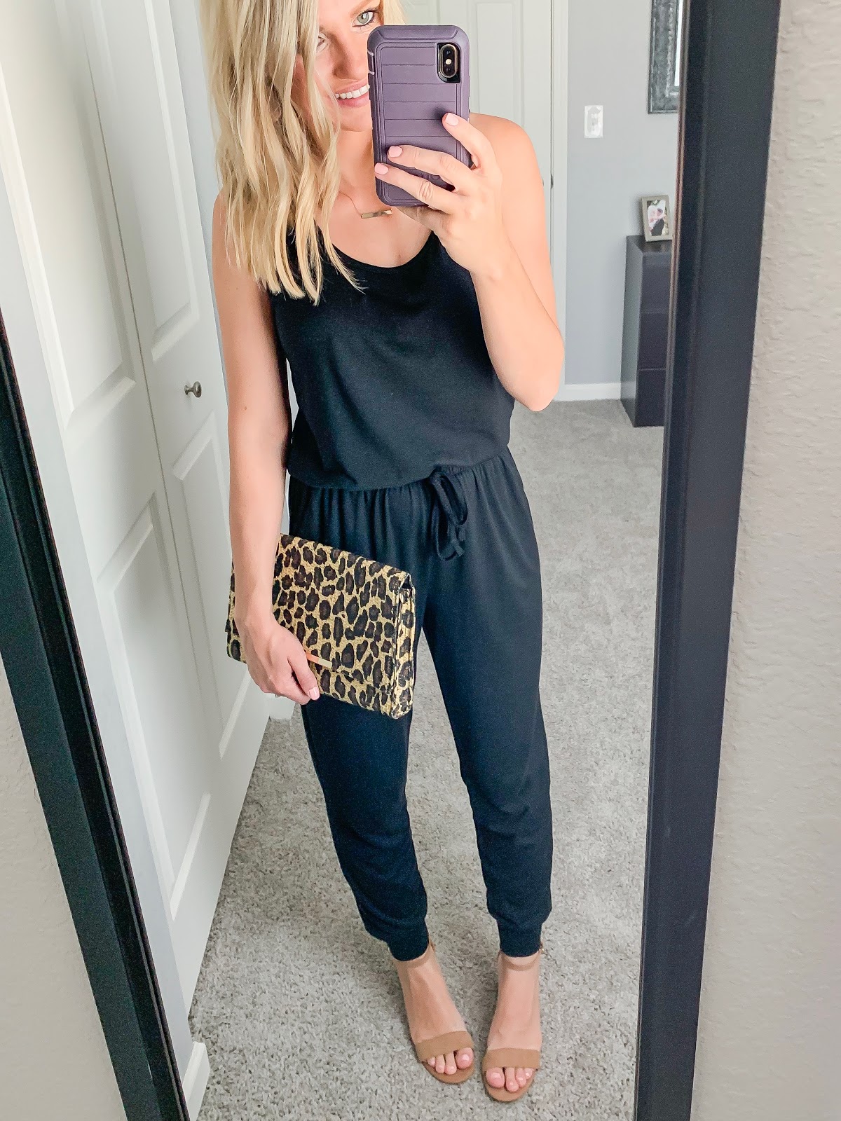 Black jumpsuit styled with a leopard clutch