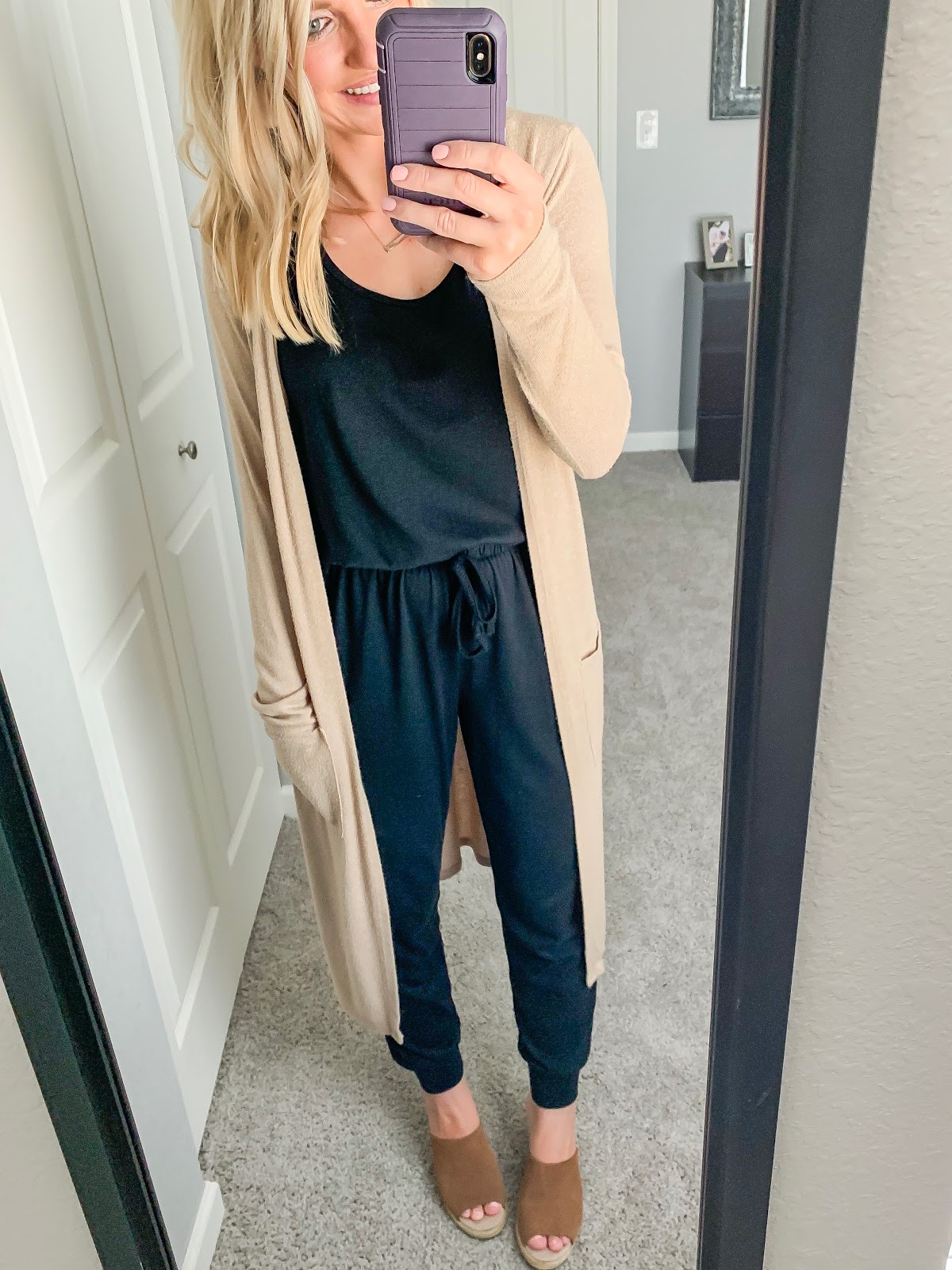 Black jumpsuit styled with a tan duster cardigan