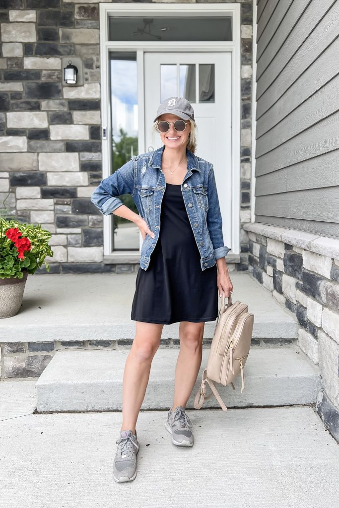 Cute mom outfit with a black athletic dress and jean jacket. 