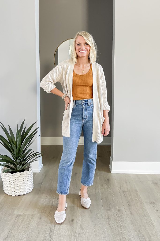 Mustard yellow shirt with medium wash jeans and a tan cardigan.