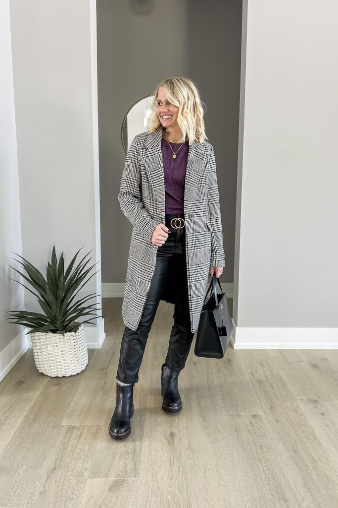 Coated black jeans styled with a purple top and a plaid coat. 
