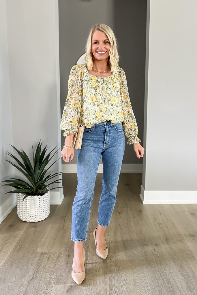 A peseant statement blouse styled with medium wash jeans. 